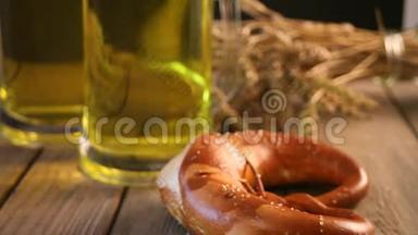女人手拿一个刚出炉的自制盐巴伐利亚椒盐卷饼。 旁边站着两杯啤酒在木桌上..
